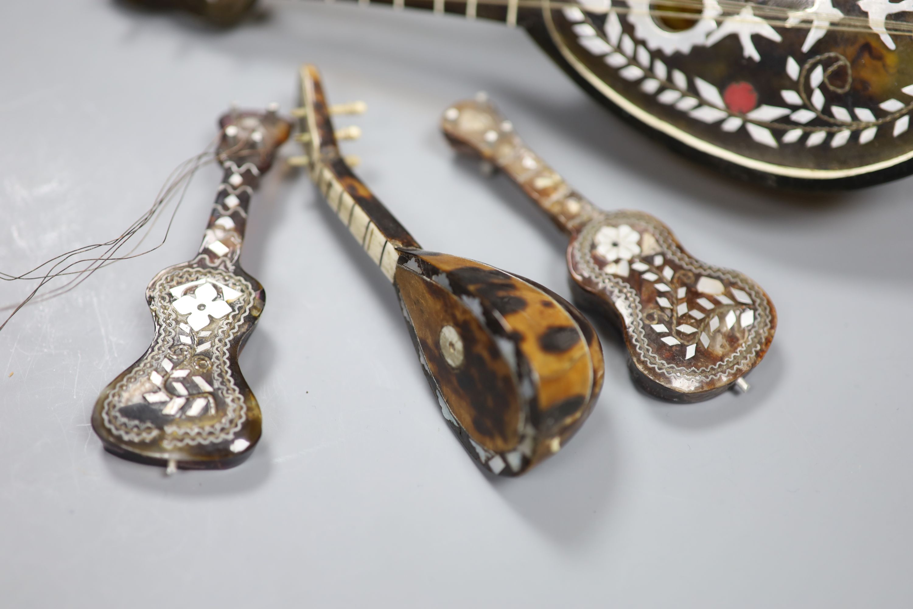 Three miniature tortoiseshell guitars and lute and a larger musical lute